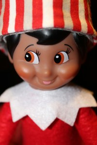 Elf doll in a red and white outfit grinning and looking to the side.